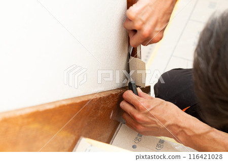 A craftsman applying wallpaper to a used house 116421028