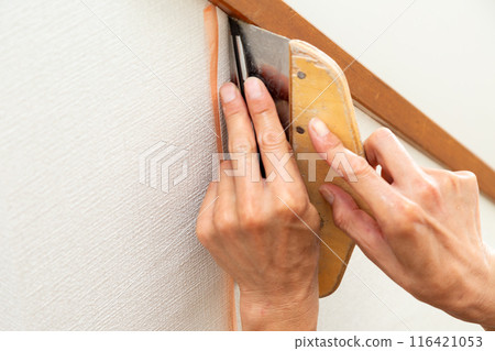 A craftsman applying wallpaper to a used house 116421053