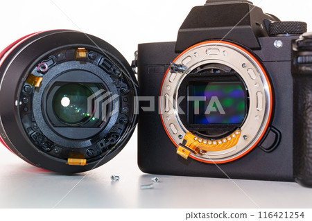 A broken lens, professional camera and repair tools on a white table. A broken lens, professional camera and repair tools on a white table. 116421254