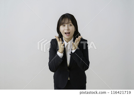 Portrait of a young woman in a suit with a surprised face against a white background Portrait of a young woman in a suit with a surprised face against a white background 116421719