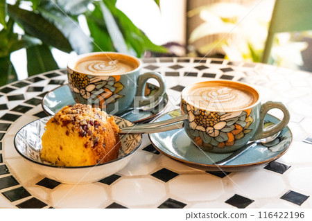 Two cuppo of coffee latte with art and cakes in a cafe with relaxing and peaceful ambient Two cuppo of coffee latte with art and cakes in a cafe with relaxing and peaceful ambient 116422196