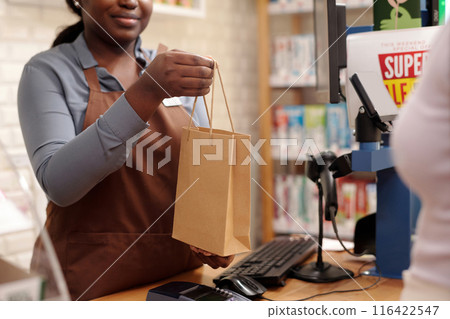 Clerk passing purchase to consumer Clerk passing purchase to consumer 116422547