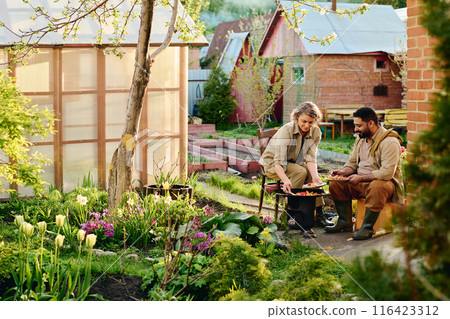 Mature farmers sitting by barrel smoker 116423312