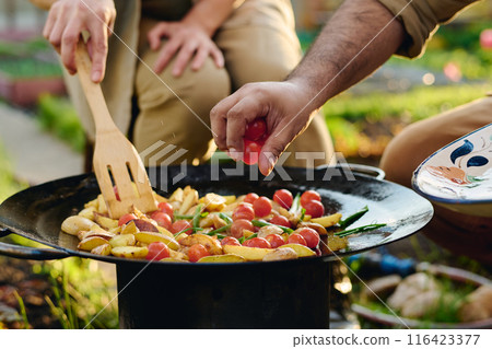 Putting tomatoes on large hot frying pan Putting tomatoes on large hot frying pan 116423377