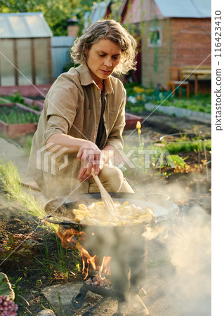 Mature female farmer cooking dinner Mature female farmer cooking dinner 116423410