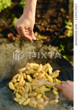Putting salt in frying pan with potatoes Putting salt in frying pan with potatoes 116423427