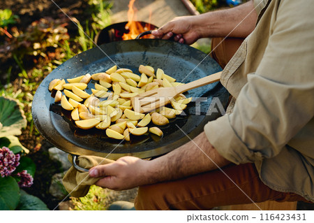 Holding frying pan with chopped potatoes 116423431