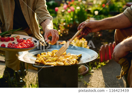 Putting and mixing chopped potatoes 116423439