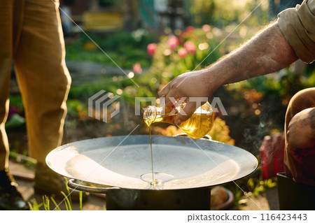 Man pouring olive oil on frying pan Man pouring olive oil on frying pan 116423443
