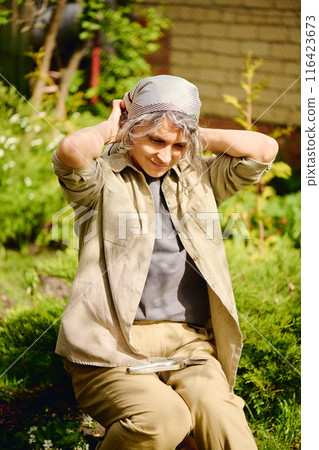 Farmer tying headscarf on back of head Farmer tying headscarf on back of head 116423673