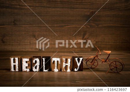 HEALTHY. Word from alphabet blocks and rusty miniature bicycle on wood texture background 116423697