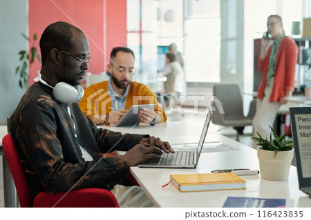 Black Man Working on Laptop with Colleagues in Office 116423835