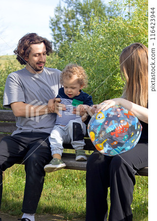 Dad, mom and little boy swinging on bench swing at playground. Family lifestyle. Kids and activity. Dad, mom and little boy swinging on bench swing at playground. Family lifestyle. Kids and activity. 116423944