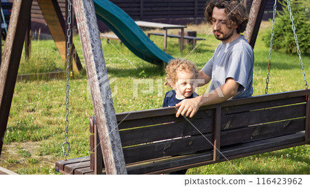 Dad and little boy swinging on bench swing at playground. Family lifestyle. Kids and activity. Dad and little boy swinging on bench swing at playground. Family lifestyle. Kids and activity. 116423962