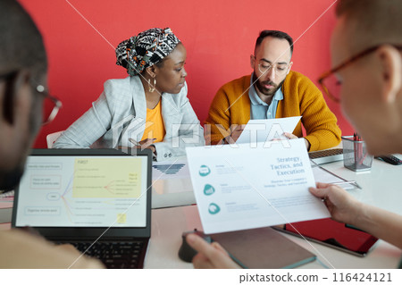 Team Reviewing Strategy Documents During Office Meeting Team Reviewing Strategy Documents During Office Meeting 116424121