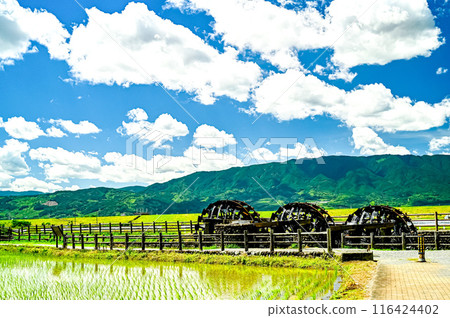 The triple waterwheel stands out against the blue sky and white clouds. 116424402