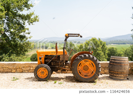 A vintage orange tractor parked in peaceful countryside in summer sunlight A vintage orange tractor parked in peaceful countryside in summer sunlight 116424656