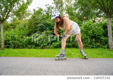 Roller skater woman warming up in park before rollerblading on inline skates. Outdoor activities. Summer roller skating. 116425192