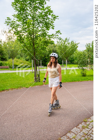 Roller skater woman in park rollerblading on inline skates. Outdoor activities. Summer roller skating. Roller skater woman in park rollerblading on inline skates. Outdoor activities. Summer roller skating. 116425202