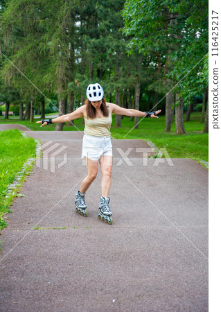 Roller skater woman in park rollerblading on inline skates. Outdoor activities. Summer roller skating. 116425217