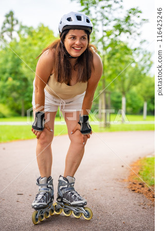 Roller skater woman in park rollerblading on inline skates. Outdoor activities. Summer roller skating. Roller skater woman in park rollerblading on inline skates. Outdoor activities. Summer roller skating. 116425246