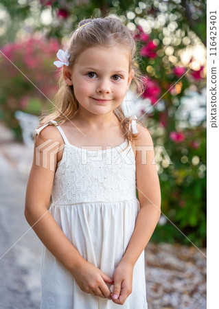 Portrait of little girl in white dress happy smiling on blooming park background in Croatia 116425401