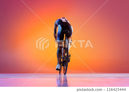 Woman, athlete in vibrant cycling attire and white helmet, leaning on road bike against gradient background in neon light. Back view 116425444