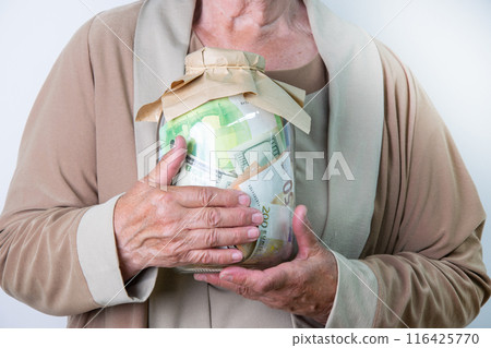 Ssenior womans hands holding a glass jar filled with various denominations of paper money Ssenior womans hands holding a glass jar filled with various denominations of paper money 116425770
