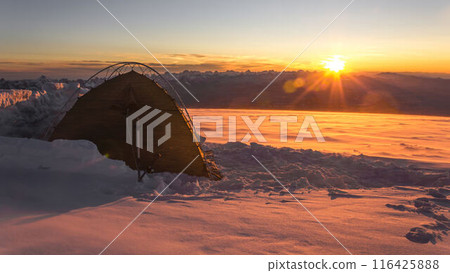 Lone tent on snowy Mount Elbrus at sunrise, climber solo travels in extreme winter conditions, explores alpine landscape amid snow storm, adventure, challenge 116425888