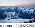 Sunset over Caucasus Range with snow peaks under colorful sky. Majestic mountain landscape in evening light. Peaceful natural scene for travel, adventure, inspiration. 116425892