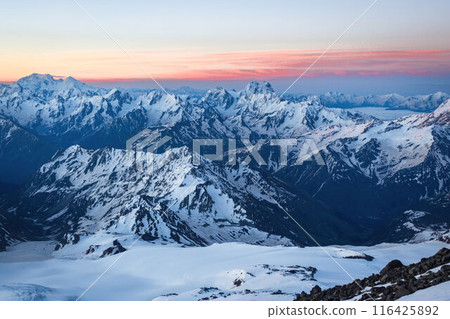 Sunset over Caucasus Range with snow peaks under colorful sky. Majestic mountain landscape in evening light. Peaceful natural scene for travel, adventure, inspiration. 116425892