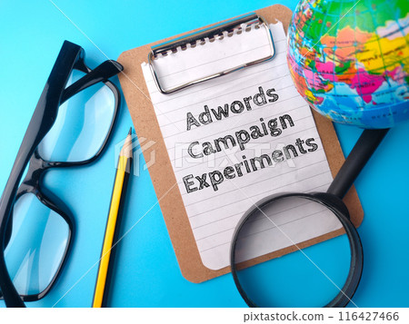 Magnifying glass,glasses,pencil and world globe with text Adwords Campaign Experiments on blue background. Magnifying glass,glasses,pencil and world globe with text Adwords Campaign Experiments on blue background. 116427466