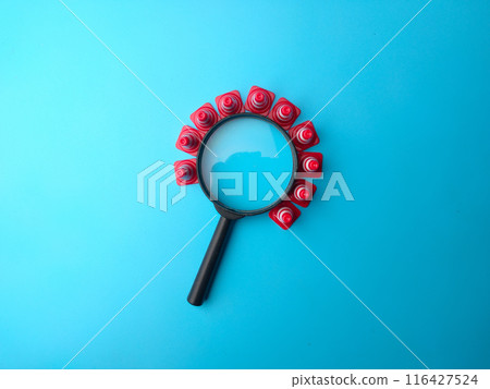 Mini plastic cones and magnifying glass on a blue background with copy and text space. Mini plastic cones and magnifying glass on a blue background with copy and text space. 116427524