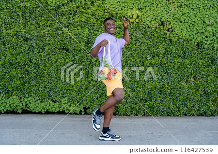 Eco friendly mesh shopper. Zero waste, plastic free concept. African man holding cotton shopper and reusable mesh shopping bags with vegetables, products. 116427539