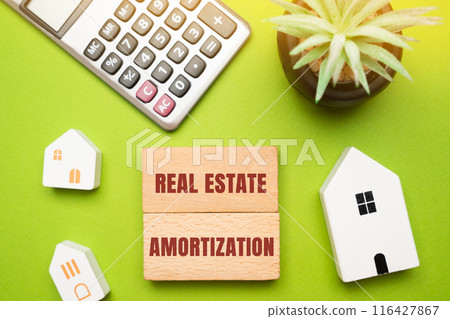 Real estate amortization concept - process of gradually paying off a mortgage or loan over a set period through regular, equal payments. Wooden blocks, houses and calculator 116427867