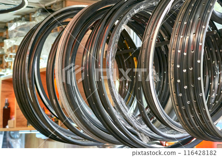 Metal rims of bicycle wheels hanging in a repair shop 116428182
