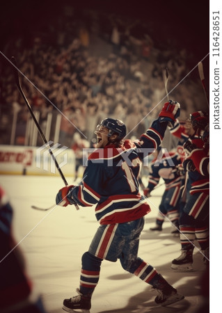 Hockey player in red celebrating a win with fists pumped in the air, illuminated by the spotlight. 116428651