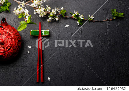 Table adorned with cherry blossom branch and chopsticks, epitomizing Japanese food culture 116429082