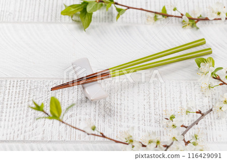 Table adorned with cherry blossom branch and chopsticks, epitomizing Japanese food culture Table adorned with cherry blossom branch and chopsticks, epitomizing Japanese food culture 116429091