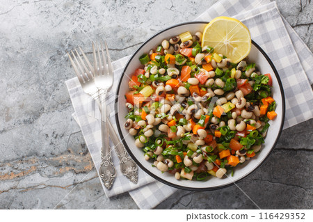 Delicious salad with black-eyed beans, carrots, onions, tomatoes, basil, parsley dressed with olive oil and lemon juice closeup on the plate. Horizontal top view Delicious salad with black-eyed beans, carrots, onions, tomatoes, basil, parsley dressed with olive oil and lemon juice closeup on the plate. Horizontal top view 116429352