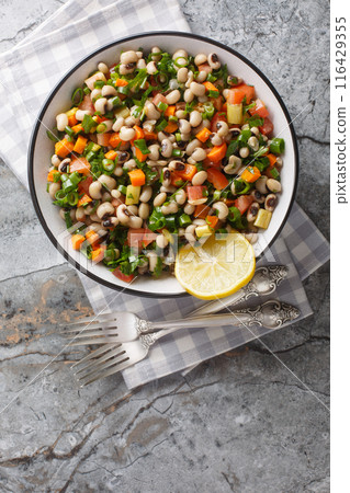 Black-eyed bean salad with carrots, onions, tomatoes, basil, parsley dressed with olive oil closeup on the plate. Vertical top view Black-eyed bean salad with carrots, onions, tomatoes, basil, parsley dressed with olive oil closeup on the plate. Vertical top view 116429355