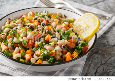 Delicious salad with black-eyed beans, carrots, onions, tomatoes, basil, parsley dressed with olive oil and lemon juice closeup on the plate. Horizontal Delicious salad with black-eyed beans, carrots, onions, tomatoes, basil, parsley dressed with olive oil and lemon juice closeup on the plate. Horizontal 116429359