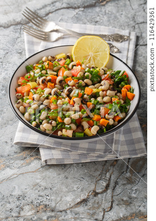 Black-eyed bean salad with carrots, onions, tomatoes, basil, parsley dressed with olive oil closeup on the plate. Vertical Black-eyed bean salad with carrots, onions, tomatoes, basil, parsley dressed with olive oil closeup on the plate. Vertical 116429361