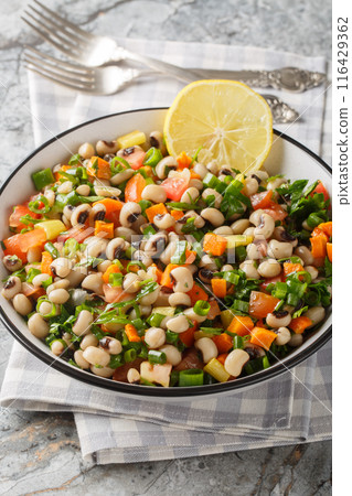 Fasolia mavromatika or black-eyed pea salad with carrot, leek, tomato and herbs closeup on the plate. Vertical Fasolia mavromatika or black-eyed pea salad with carrot, leek, tomato and herbs closeup on the plate. Vertical 116429362
