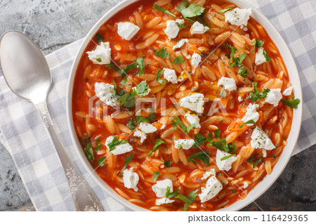 Traditional Greek pasta kritharaki or orzo with spicy tomato sauce, cheese, garlic, onion, carrots closeup on the plate. Horizontal top view 116429365