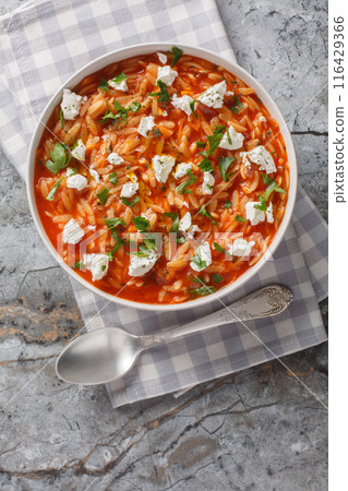 Greek pasta kritharaki or orzo with tomato sauce, feta, onion and herbs closeup on the plate. Vertical top view 116429366