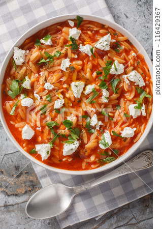One-pot Greek orzo kritharaki with tomatoes and Feta cheese is a delicious weeknight dish and a comfort food in Greece closeup on the plate. Vertical top view 116429367