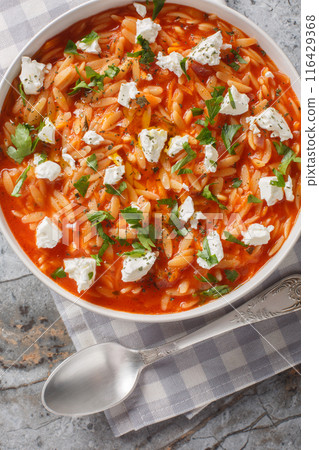 Mediterranean cuisine orzo pasta with spicy tomato sauce, feta, garlic, onion, carrots closeup on the plate on the table. Vertical top view Mediterranean cuisine orzo pasta with spicy tomato sauce, feta, garlic, onion, carrots closeup on the plate on the table. Vertical top view 116429368