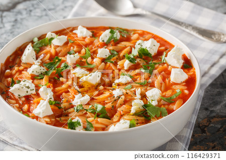 Traditional Greek pasta kritharaki or orzo with spicy tomato sauce, cheese, garlic, onion, carrots closeup on the plate. Horizontal 116429371