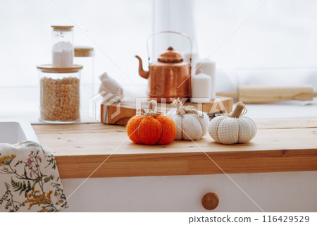 Bright kitchen with wooden furniture with kitchen utensils and three decorative pumpkins. Bright kitchen with wooden furniture with kitchen utensils and three decorative pumpkins. 116429529